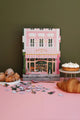 Close-up of Pink Bakery puzzle by All the Ways to Say, featuring a detailed Parisian storefront with pink and green tones and gold accents.
