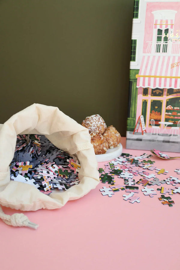 Cup of espresso with a few Pink Bakery puzzle pieces on the saucer — cozy breakfast puzzle setup by All the Ways to Say.
