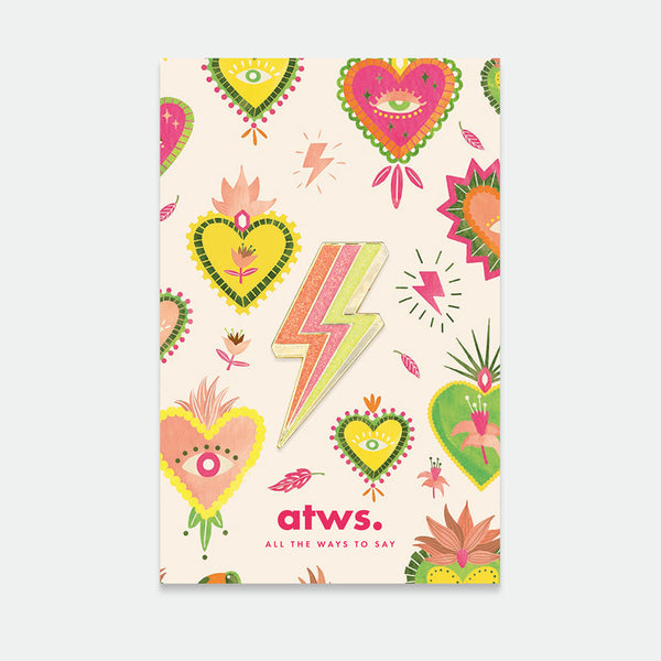 Lightning Bolt enamel pin by All the Ways to Say featuring glittery gold and pink bolt design on colorful illustrated background with hearts and flowers.