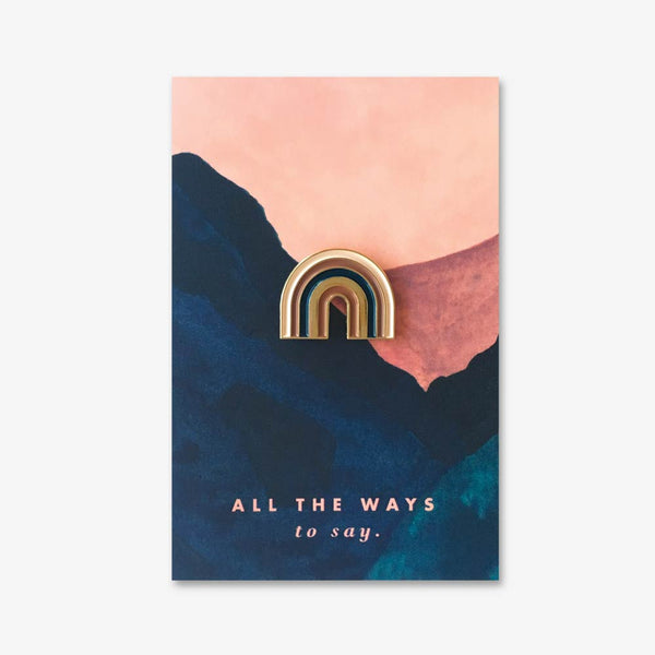 Rainbow enamel pin by All the Ways to Say featuring a minimalist gold-plated rainbow design with soft tones, ideal for jackets, totes, or gifting.