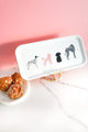 White coffee tray featuring four dog illustrations, styled on marble with golden stand and pastries on the side.