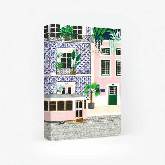 1000-piece jigsaw puzzle box by All The Ways To Say featuring a colorful Lisbon street scene with a pink tram and buildings decorated with blue azulejos tiles.