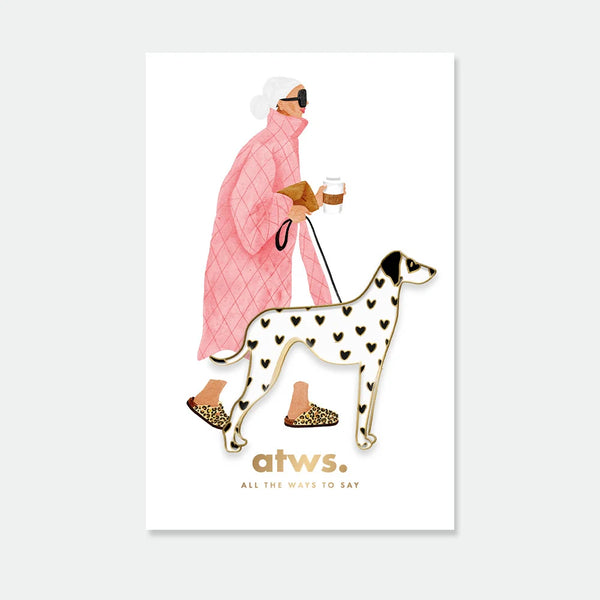A white Dalmatian enamel pin by All The Ways To Say with black heart spots and gold outlines, displayed on an illustration of a woman in a pink coat.
