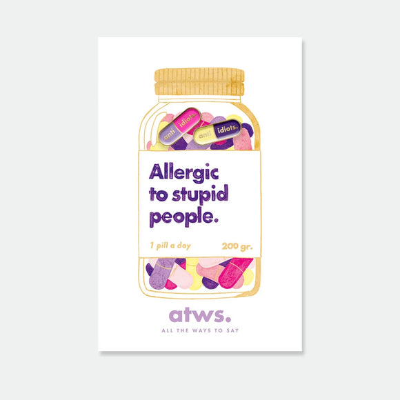 A duo of small gold enamel pins shaped like colorful capsules with the text "anti idiots", displayed on a pill jar themed card.
