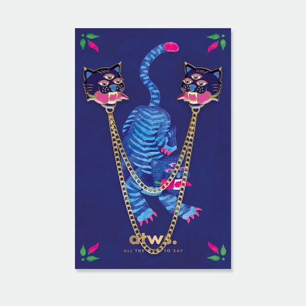 A mystical set of two blue tiger head enamel pins connected by two gold chains, displayed on a dark blue card with a tiger illustration.