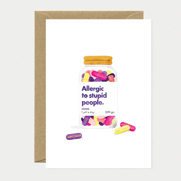 A humorous greeting card by All The Ways To Say featuring a watercolor jar of colorful "anti-idiot" pills with the text "Allergic to stupid people."