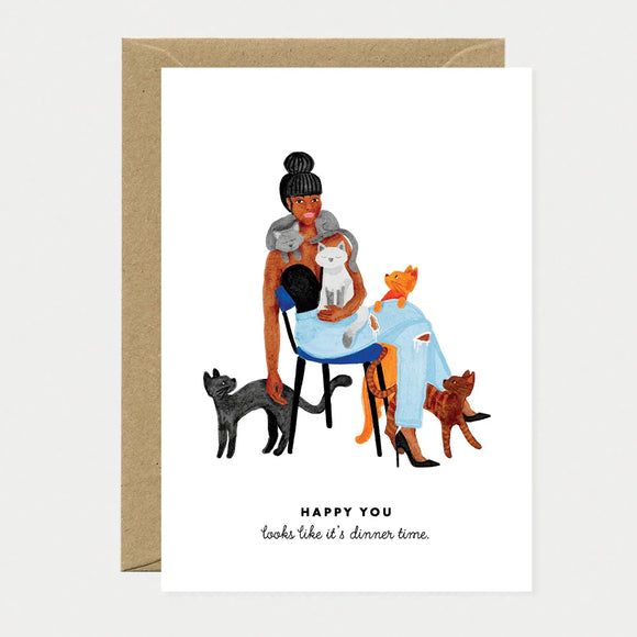 A humorous greeting card by All The Ways To Say featuring a watercolor illustration of a woman covered in several cats with the text "HAPPY YOU looks like it's dinner time."