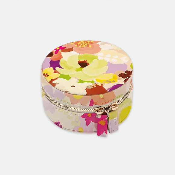 A round travel jewellery box by All The Ways To Say featuring a colorful watercolor floral print on a light background with a gold zipper.