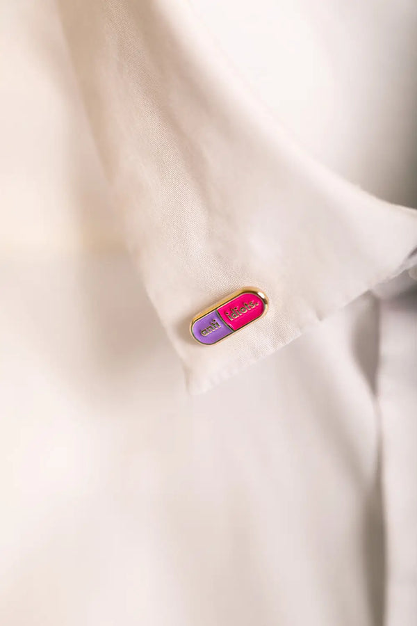 Duo Anti Idiots - Pins: the pink and light purple enamel pin displayed on a white button-down shirt.