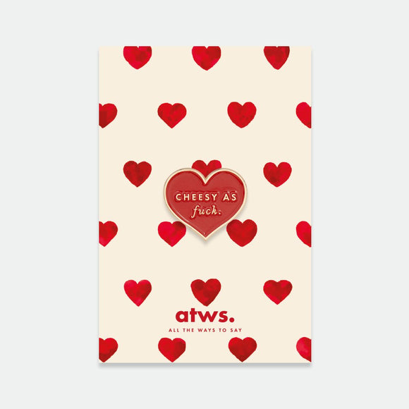 Cheesy as fuck enamel pin by All the Ways to Say featuring red heart with gold lettering on illustrated cream and red heart background.