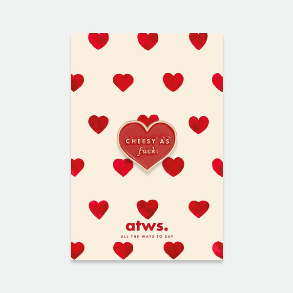 Cheesy as fuck enamel pin by All the Ways to Say featuring red heart with gold lettering on illustrated cream and red heart background.
