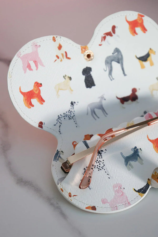 Open dog-pattern glasses case showing pink-rimmed sunglasses inside.