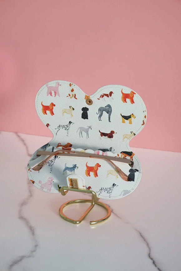 Open glasses case with colorful dog illustrations, displayed on a gold stand.