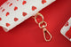 Close-up of a red hearts patterned glasses case with golden clasp detail on a red background