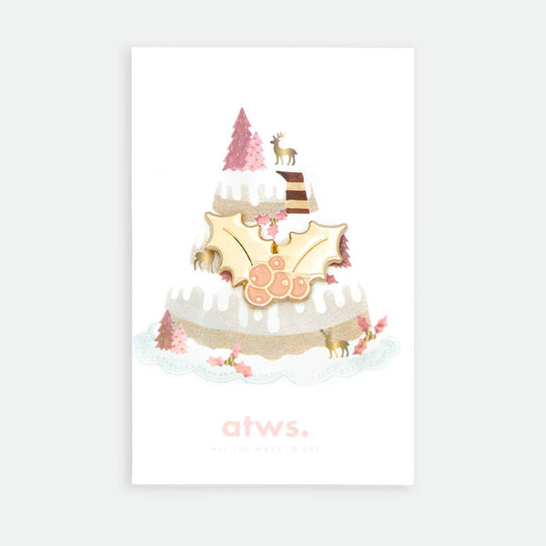 Holly Berry enamel pin by All the Ways to Say featuring gold-plated holly leaves and red berries on illustrated snowy Christmas cake background.