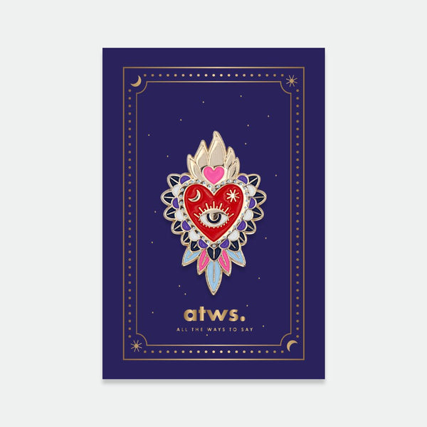 Ex-Voto enamel pin by All the Ways to Say featuring red sacred heart with gold flames, eye detail, and floral pattern on dark blue celestial background.