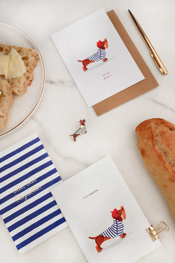 Parisian-inspired Frenchie collection by All The Ways To Say – dachshund enamel pin, notebooks and greeting card on marble background