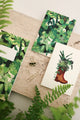Flatlay of Green Cliff notebooks and stationery with tropical leaves and plant illustrations.