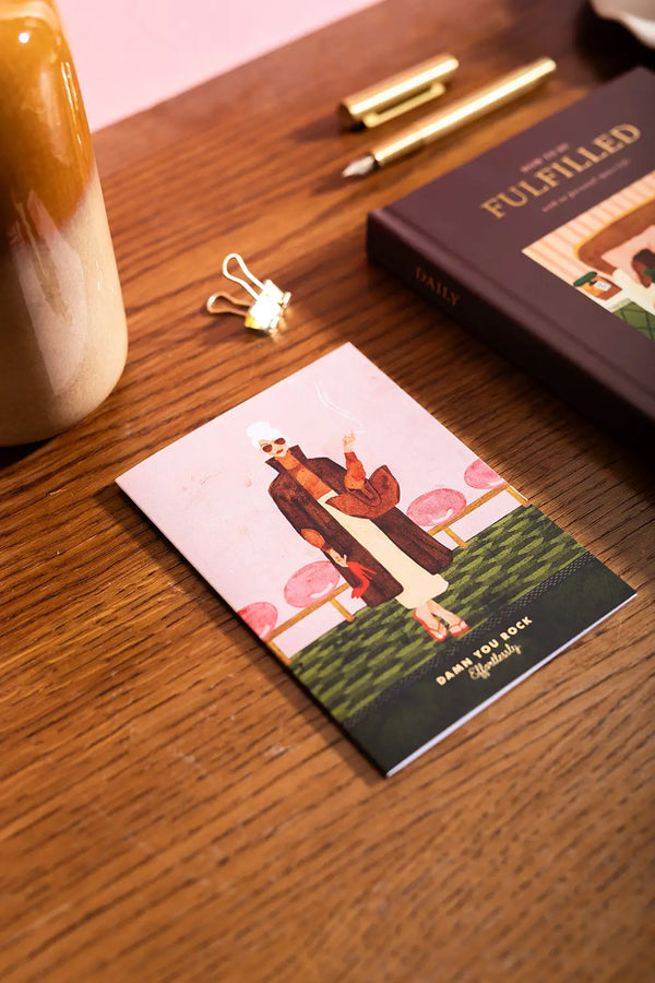 Damn you rock Greeting card - Lifestyle view of the hand-painted fashion illustration on a wooden desk with gold accessories.