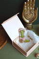Hand-embroidered cowboy boot brooch in pink and lime green silk threads with gold beads, displayed in a light pink gift box.