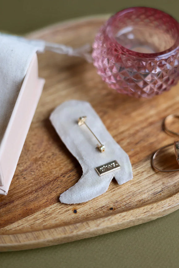 Reverse side of the handmade boot brooch showing the secure gold metal pin clasp and soft beige velvet backing.