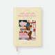 JOMO hardcover A5 notebook by All The Ways To Say, pale yellow cover styled like a book jacket with the title "The Joy Of Missing Out, for people with better plans," a fake author credit, and an illustration of a woman pumping gas at a retro gas station with three dogs in a pink convertible