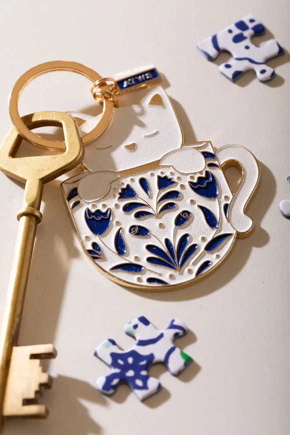 Cat in a mug Keychain - Detailed focus on the cat's face and the intricate blue mug patterns.