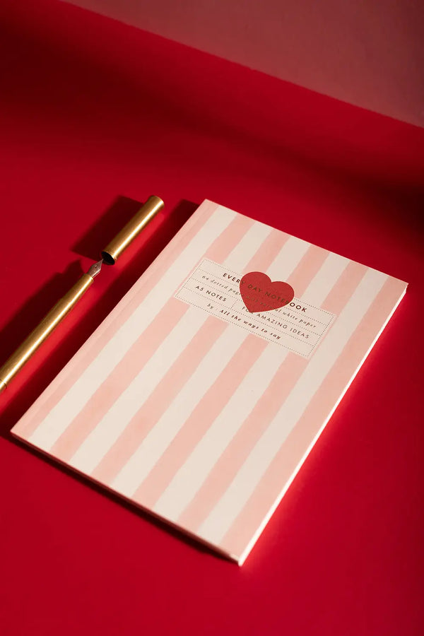 Pink stripes Notebook A5 - Full view on a red background with a golden fountain pen.
