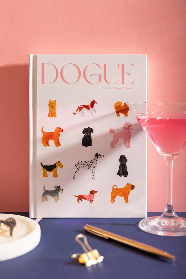 Dogue Hardcover Notebook A5 - Front view on a navy background with a pink cocktail and gold pen.