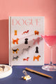Dogue Hardcover Notebook A5 - Front view on a navy background with a pink cocktail and gold pen.