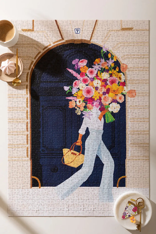 Parisian Door - Puzzle 1000 pieces: a complete view of the assembled puzzle featuring a woman with a large floral bouquet at a navy door.
