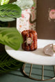 Duo Scarabée - Pins: a pink enamel beetle pin with a heart detail displayed on a French canelé pastry.