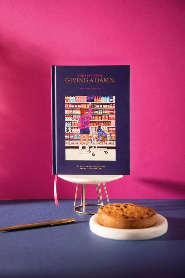 "The art of not giving a damn" A5 hardcover notebook in navy, cover showing a girl in a pink jacket reaching for jam in a grocery aisle