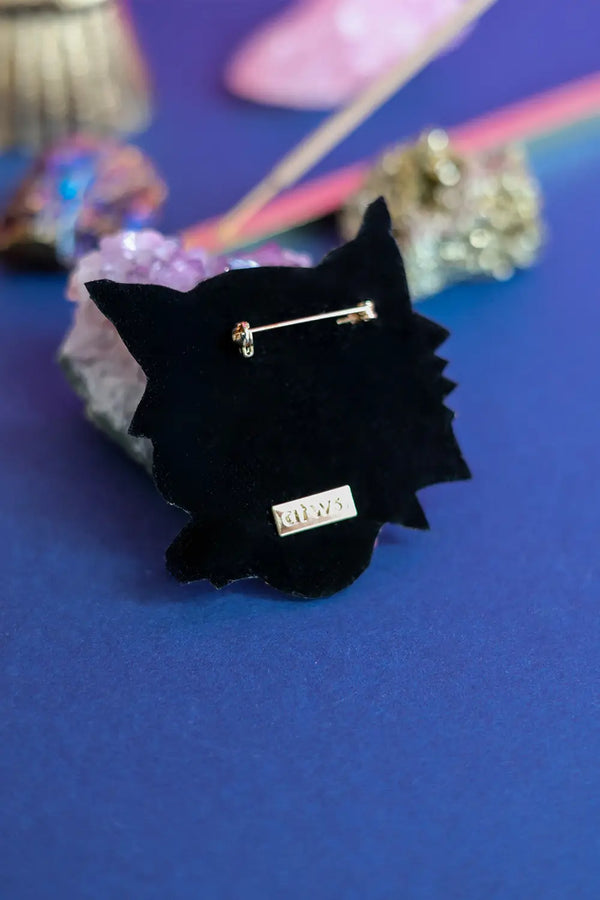 Back view of the tiger brooch showing the black velvet finish, secure gold safety pin clasp, and designer brand metal tag.