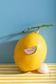 Watermelon - Pins: the glittery watermelon pin creatively displayed on a fresh yellow lemon against a blue background.